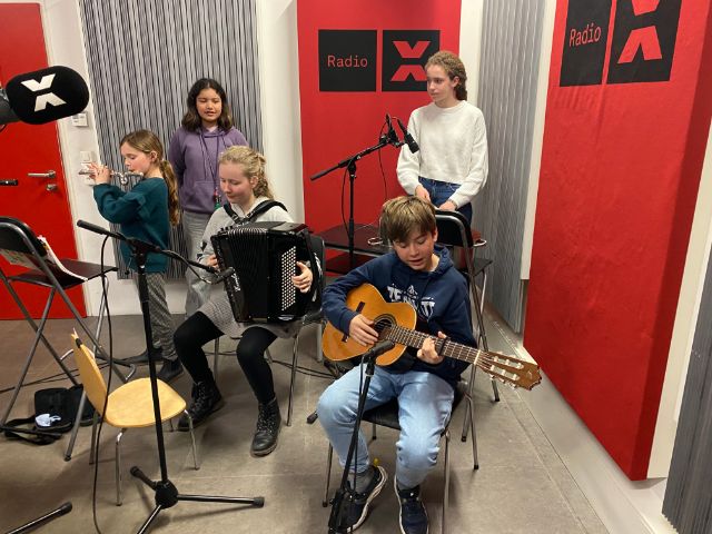 fünf Kinder im Studio mit Gitarre, Akkordeon, Querflöte, Perkussion und singend